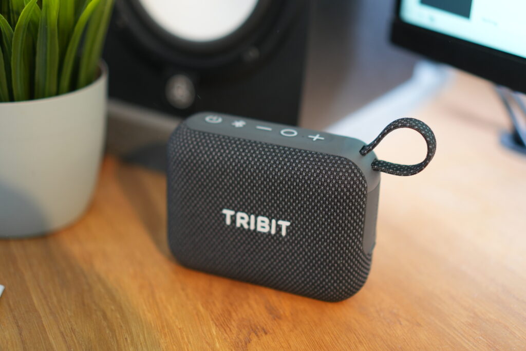 Tribit PocketGo schwarzer kompakter Mini-Bluetooth-Lautsprecher mit Stofffront, silbernen Bedienelementen auf der Oberseite, Schlaufe aus Textil, kompaktes ABS-Gehäuse