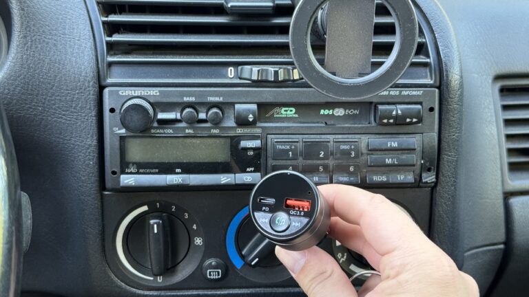 In einem älteren Auto hält eine Hand den Mohard BC61 FM Transmitter vor dem originalen Grundig-Radio, um Bluetooth 5.3 per FM nachzurüsten.