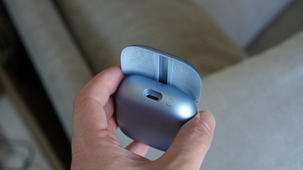 Mattblaues Ladecase der Soundcore Liberty 5 Pro von Anker mit geöffnetem Deckel und USB‑C-Anschluss in einer Hand, passend zu den 180-Euro-In-Ears.