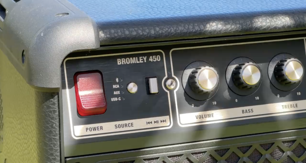 Schwarzes Bedienfeld des Marshall Bromley 450 mit rotem Power-Schalter, goldenen Drehreglern für Volume, Bass und Treble sowie Source-Taste.