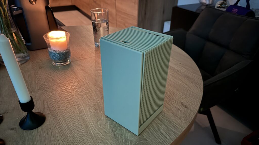 Auf dem Tisch steht der kompakte Wanbo Cube 2 Pro, ein Full-HD-Beamer mit würfelförmigem Design und drehbarem Gimbal-Standfuß in Beigegrün.