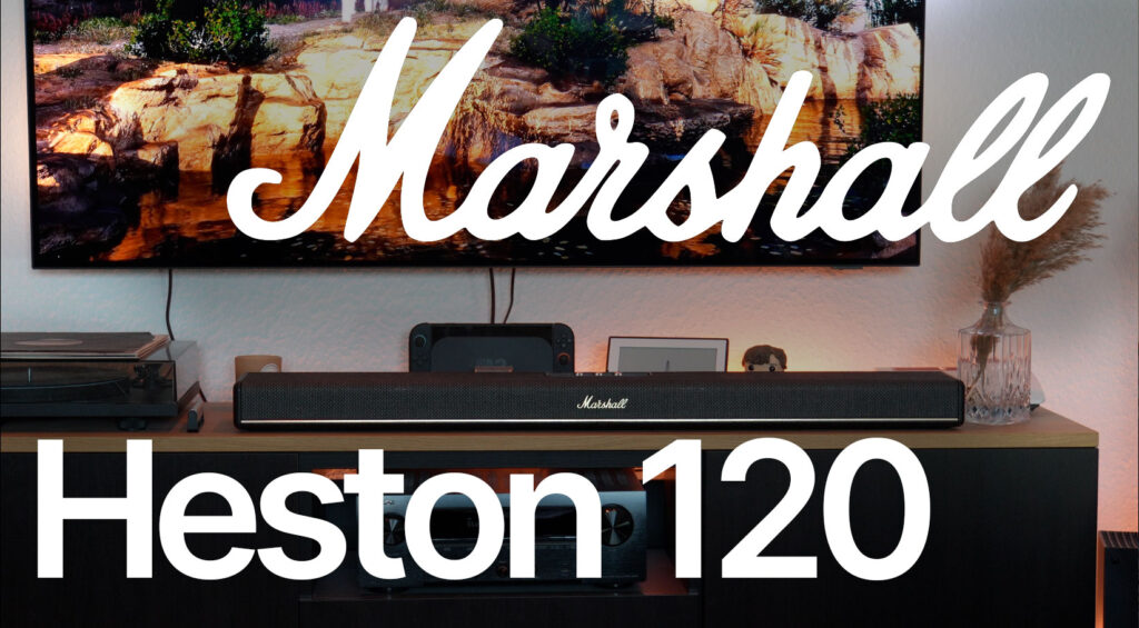 Eine schwarze Marshall Heston 120 steht unter dem Fernseher in einem Wohnzimmer mit Konsole, Verstärker und warmem Ambientelicht.