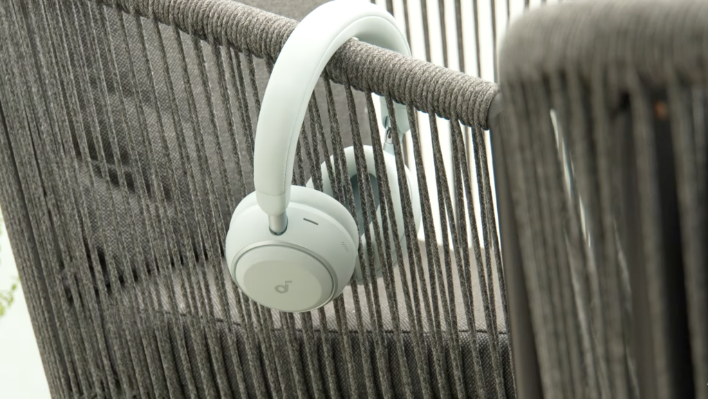 Die weißen Soundcore Space 2 hängen am Stuhllehnengeflecht und zeigen das Over-Ear-Design mit aktivem Noise Cancelling für den Testbericht.